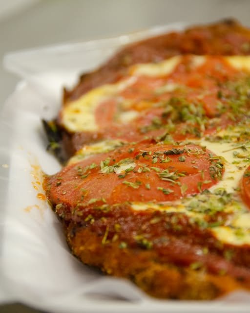 Porción de milanesa con tomate, recién servida